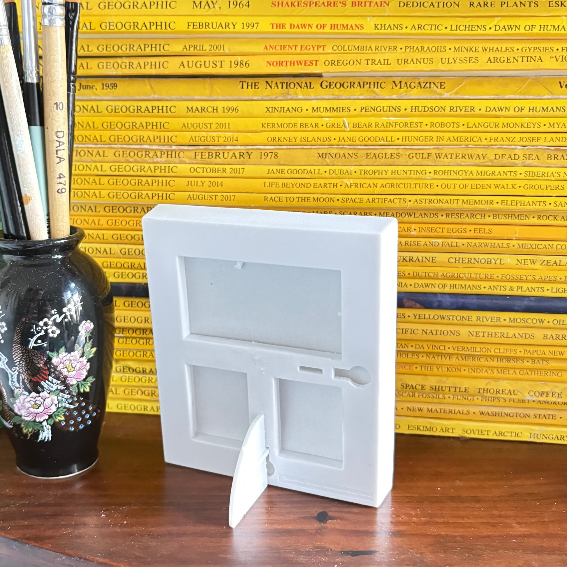 Desk with books, a vase, and stationery items against a yellow wall.