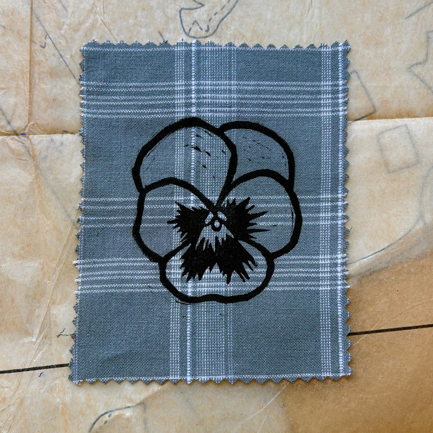 Fabric swatch with a black floral design on a beige background