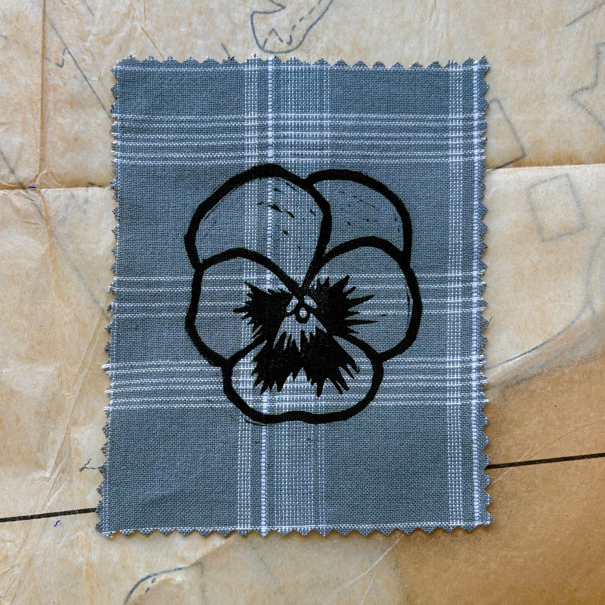 Fabric swatch with a black floral design on a beige background
