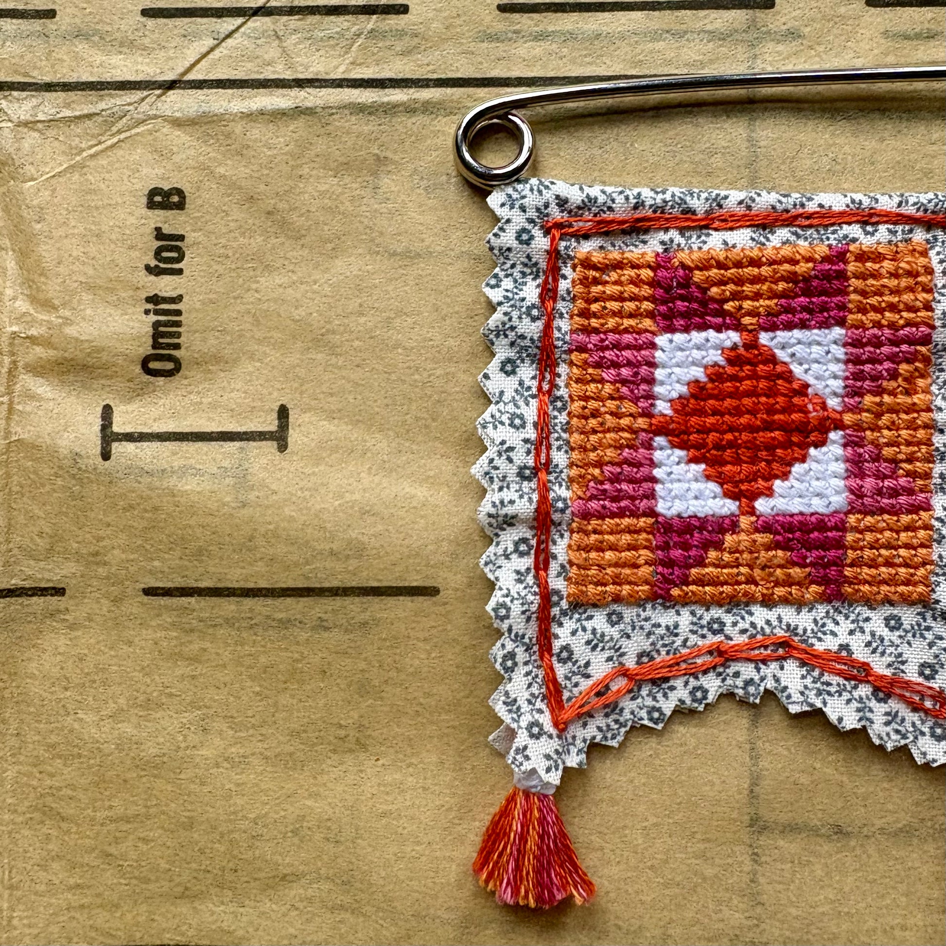 Cross-stitched patch with a geometric pattern on a cardboard surface