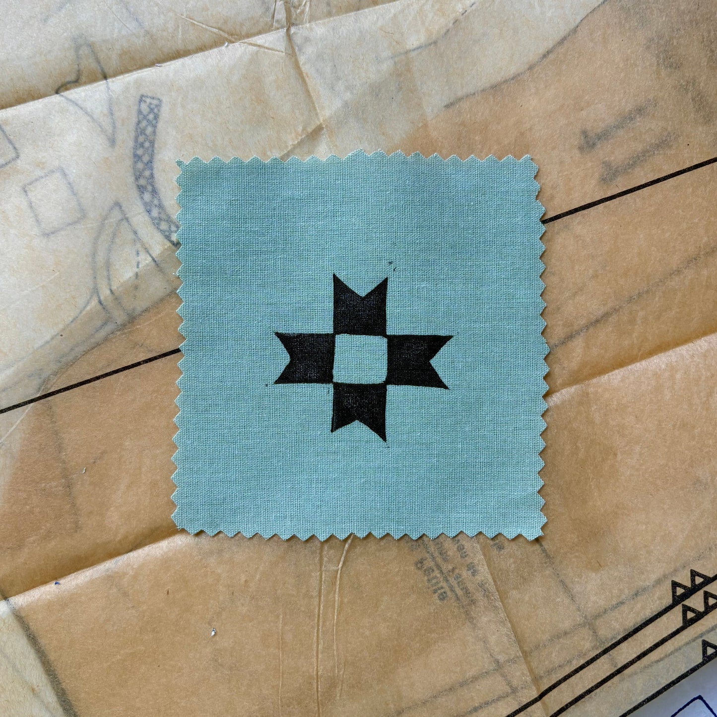 Square patch with a black star design on a textured beige surface
