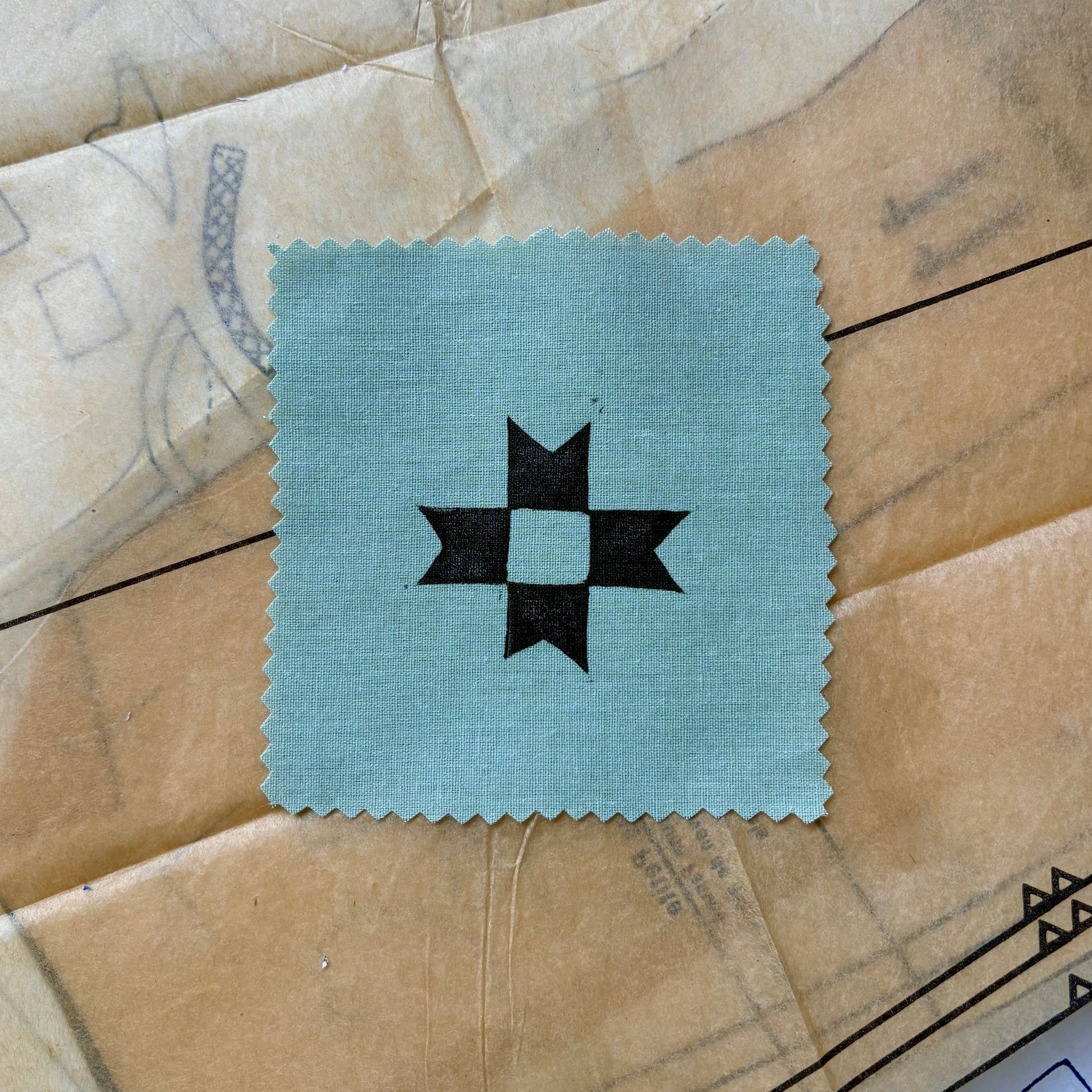 Square patch with a black star design on a textured beige surface