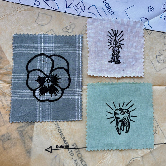 Textile samples with embroidered designs on a patterned fabric background