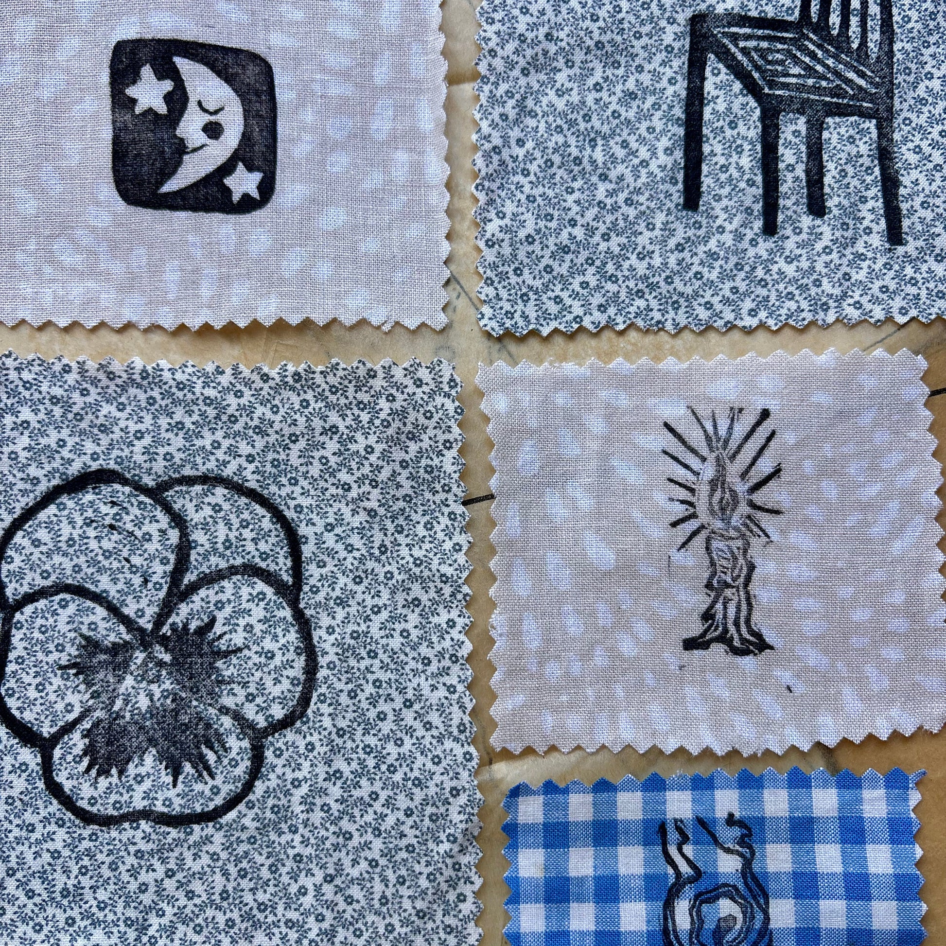 Collection of fabric squares with black line art on a cardboard background