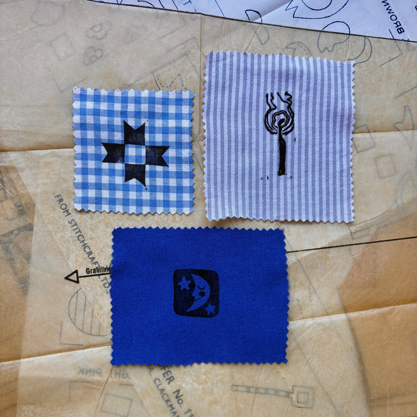 Three fabric swatches with embroidered designs on a patterned surface