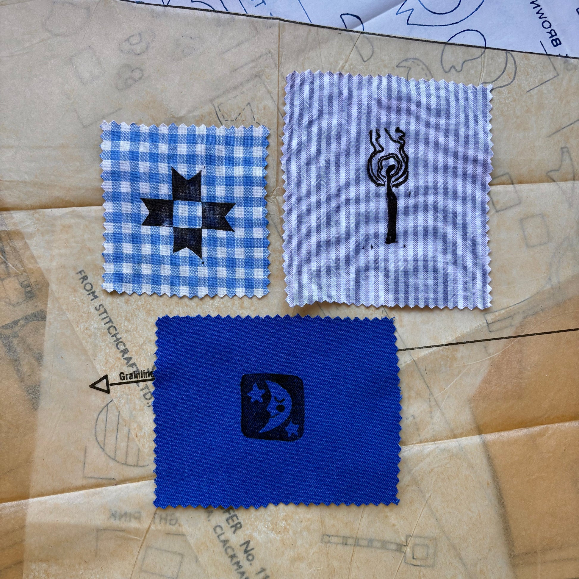 Three fabric swatches with embroidered designs on a patterned surface