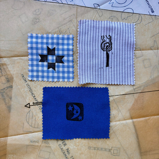 Three fabric swatches with embroidered designs on a patterned surface