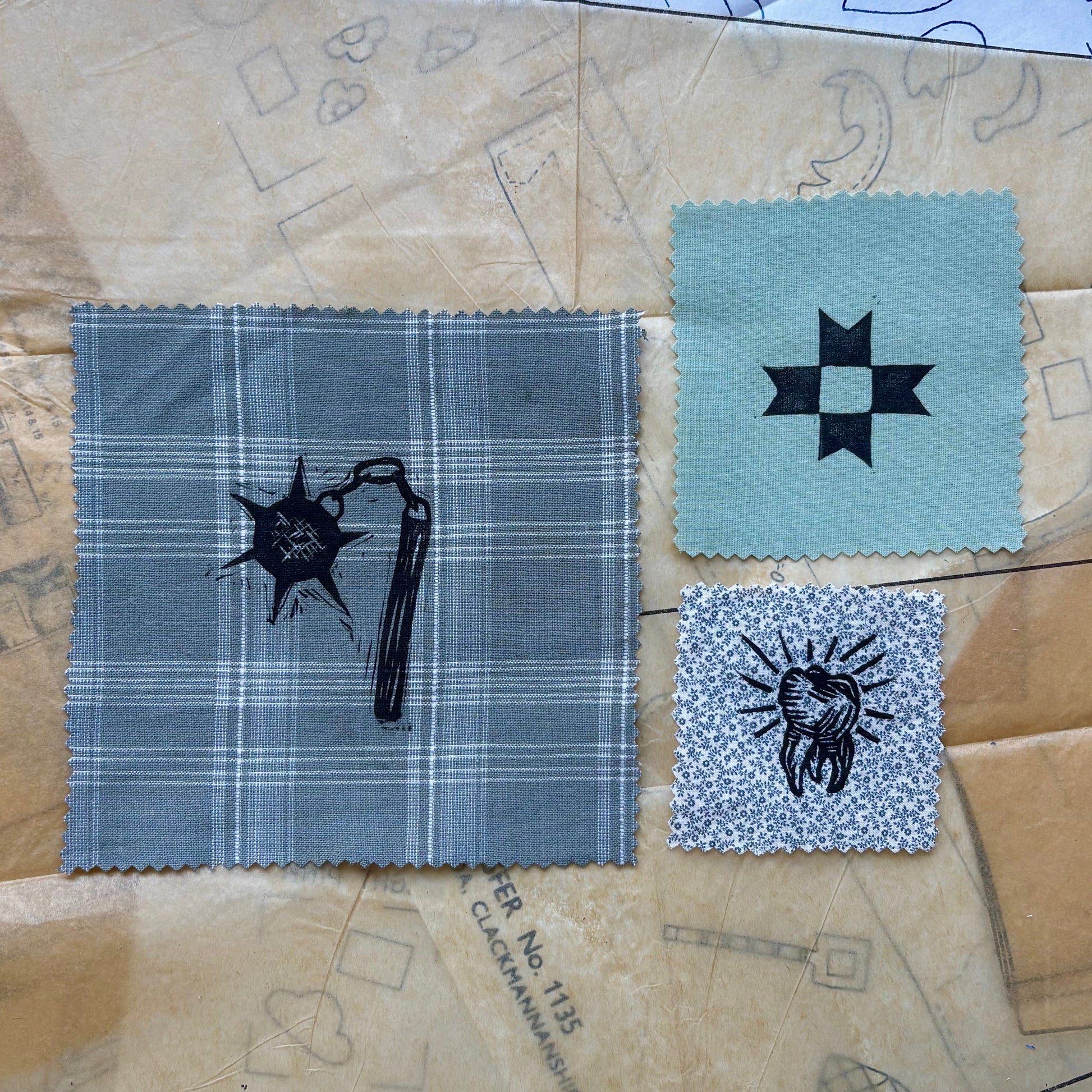 Fabric swatches with embroidered designs on a patterned paper background