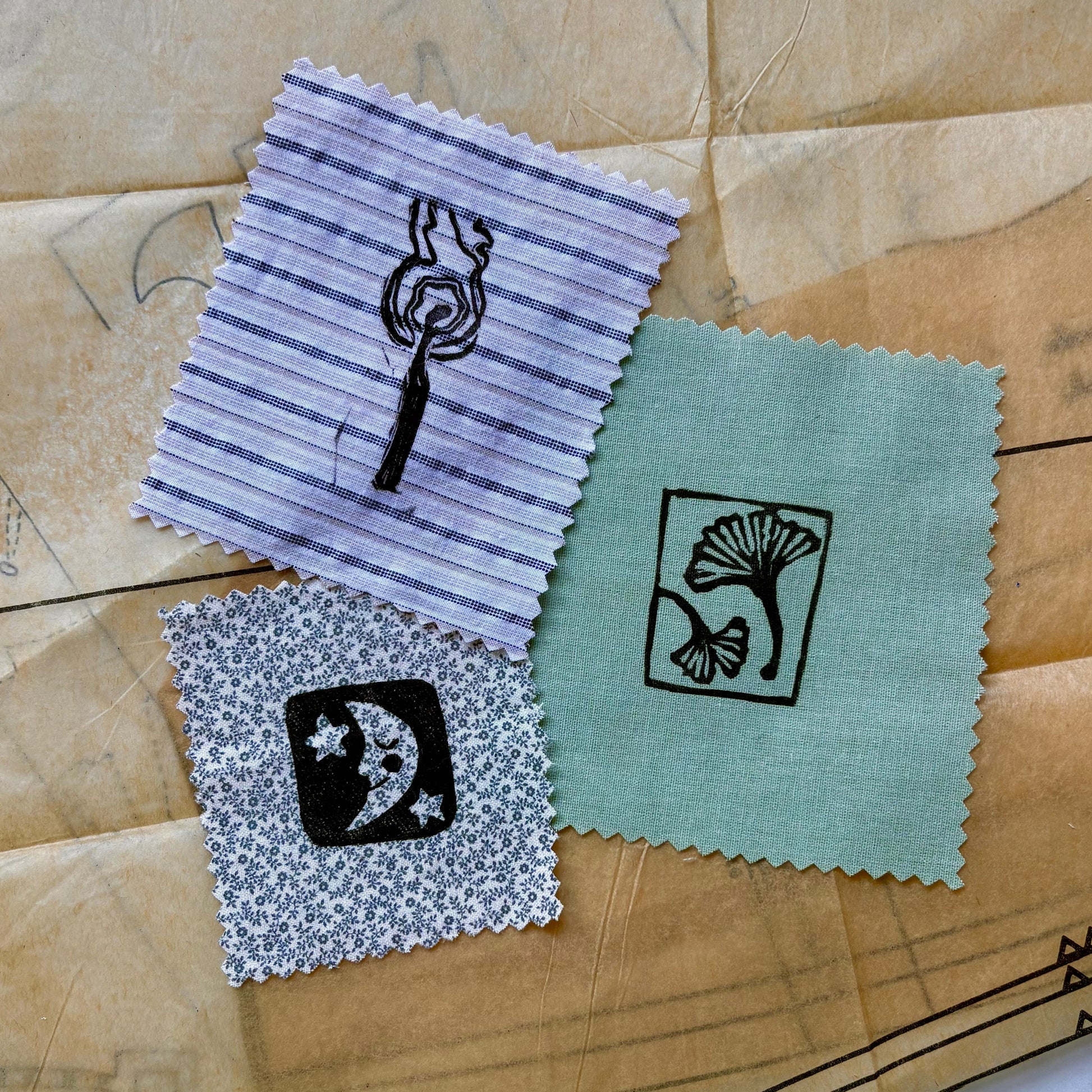 Four fabric swatches with printed designs on a patterned surface