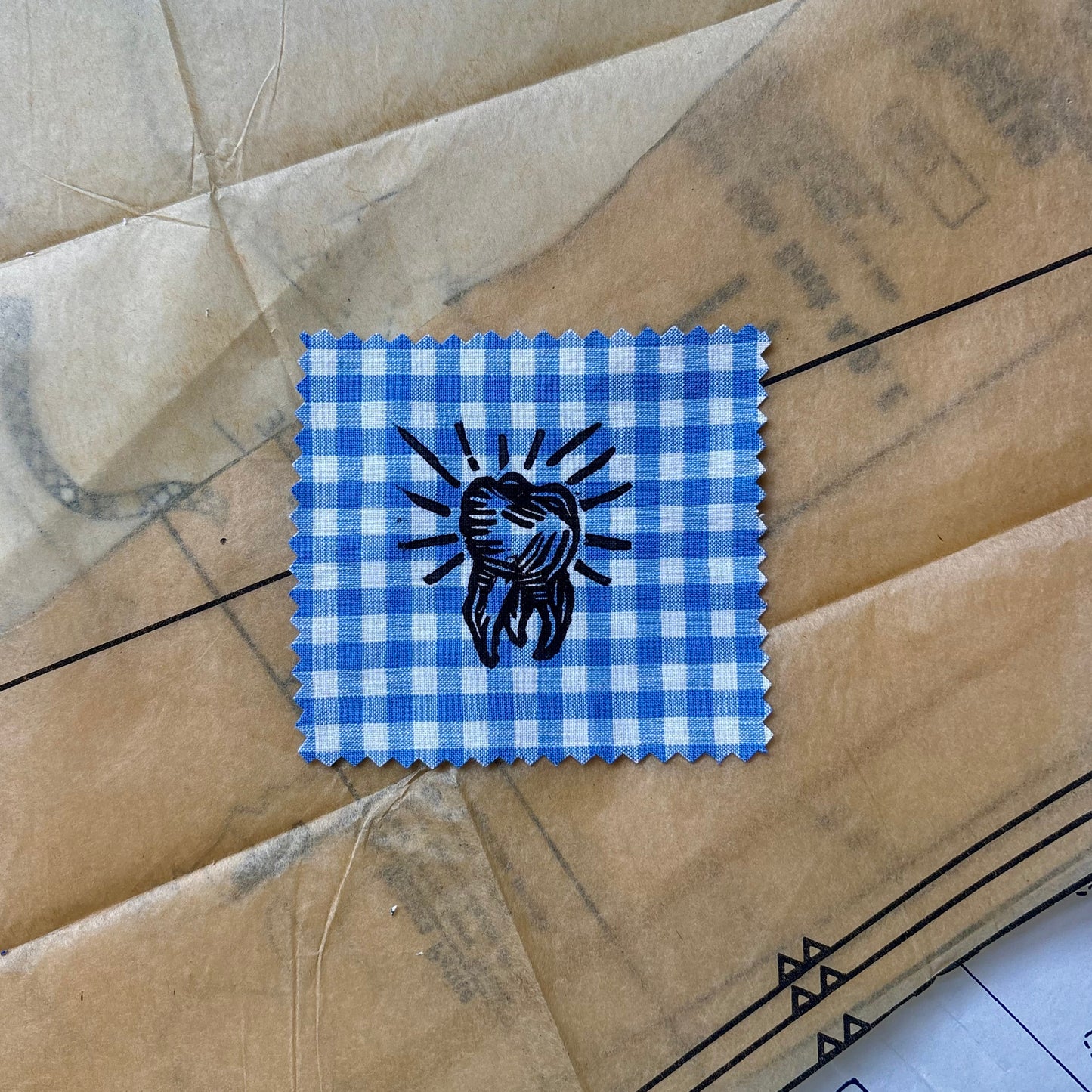 Blue checkered patch with a black design on a brown surface