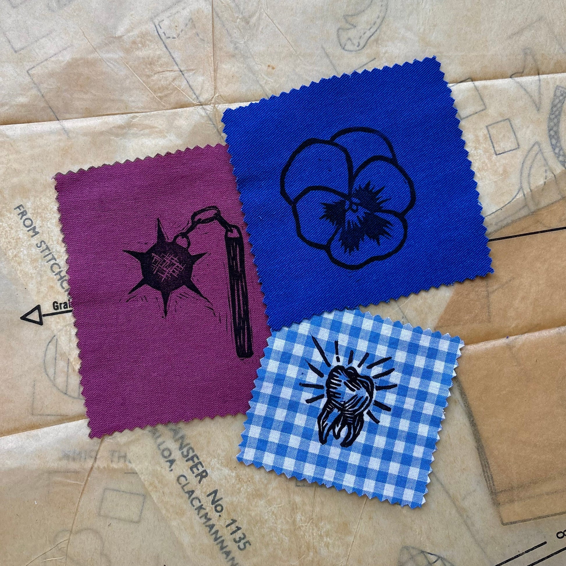 Three fabric swatches with printed designs on a cardboard surface