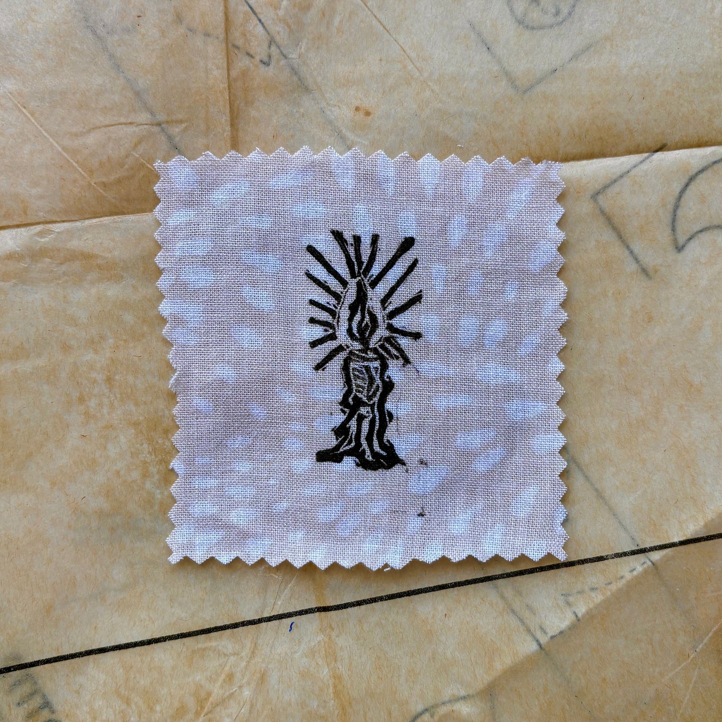 White cloth square with black design on a textured beige surface