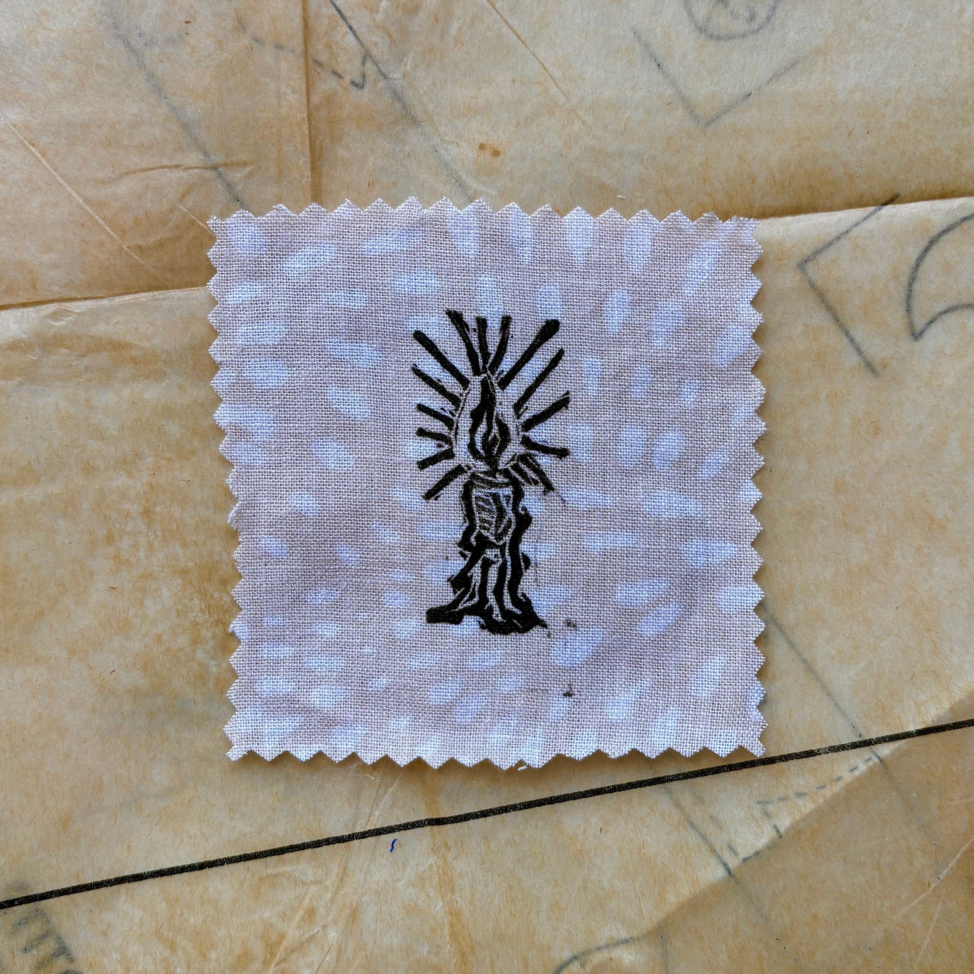White cloth square with black design on a textured beige surface