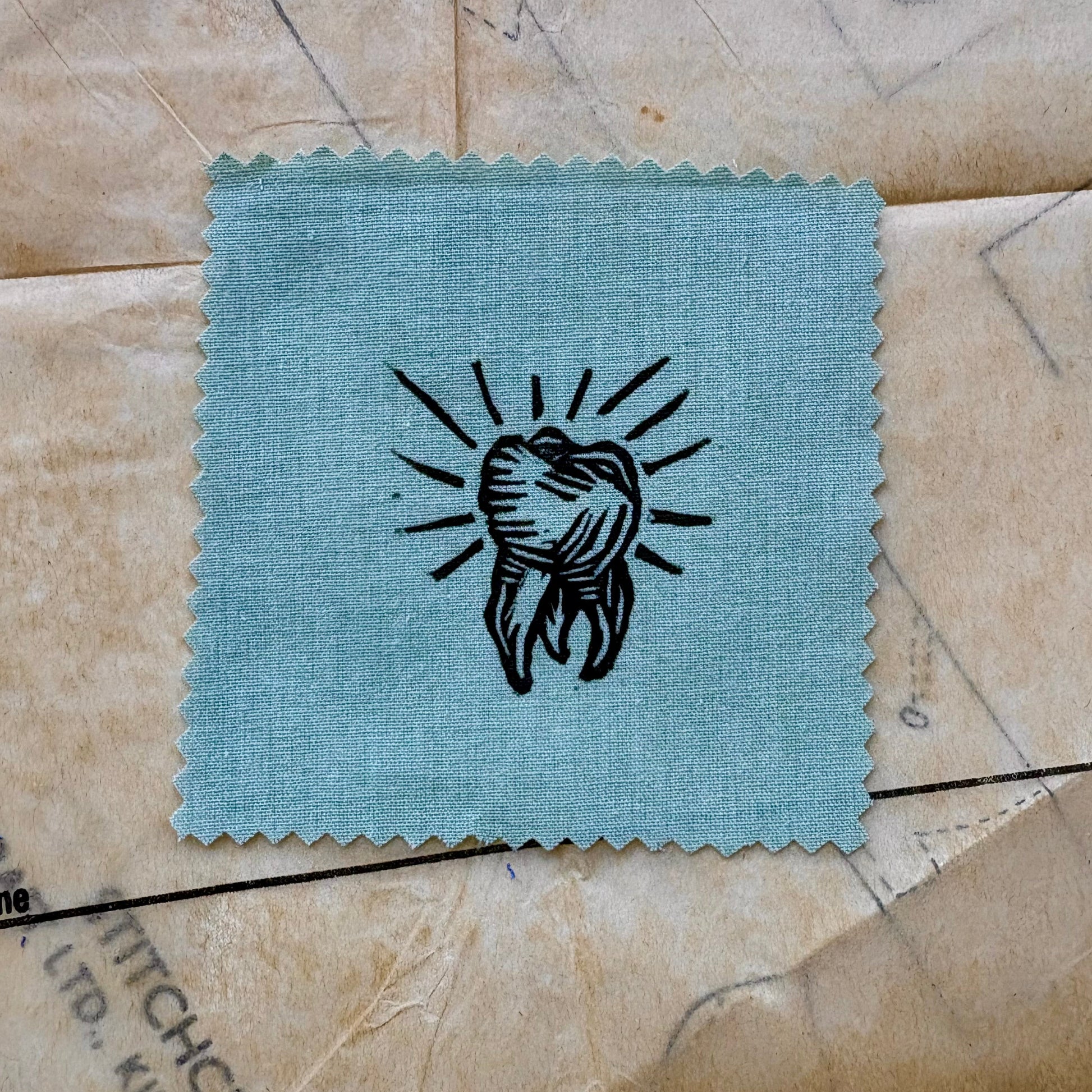 Small blue fabric swatch with a black design on a textured surface