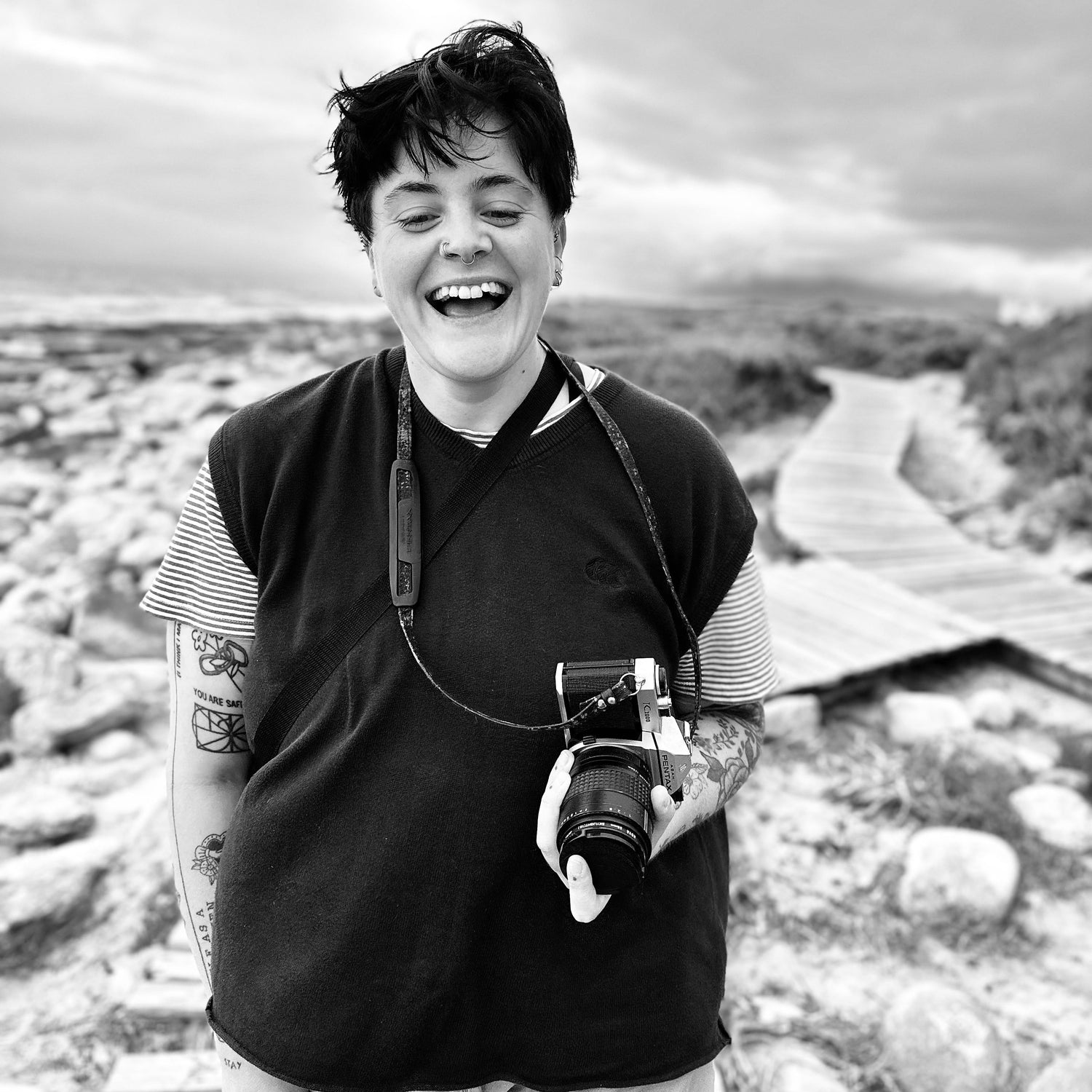 Person holding a camera outdoors with a scenic background